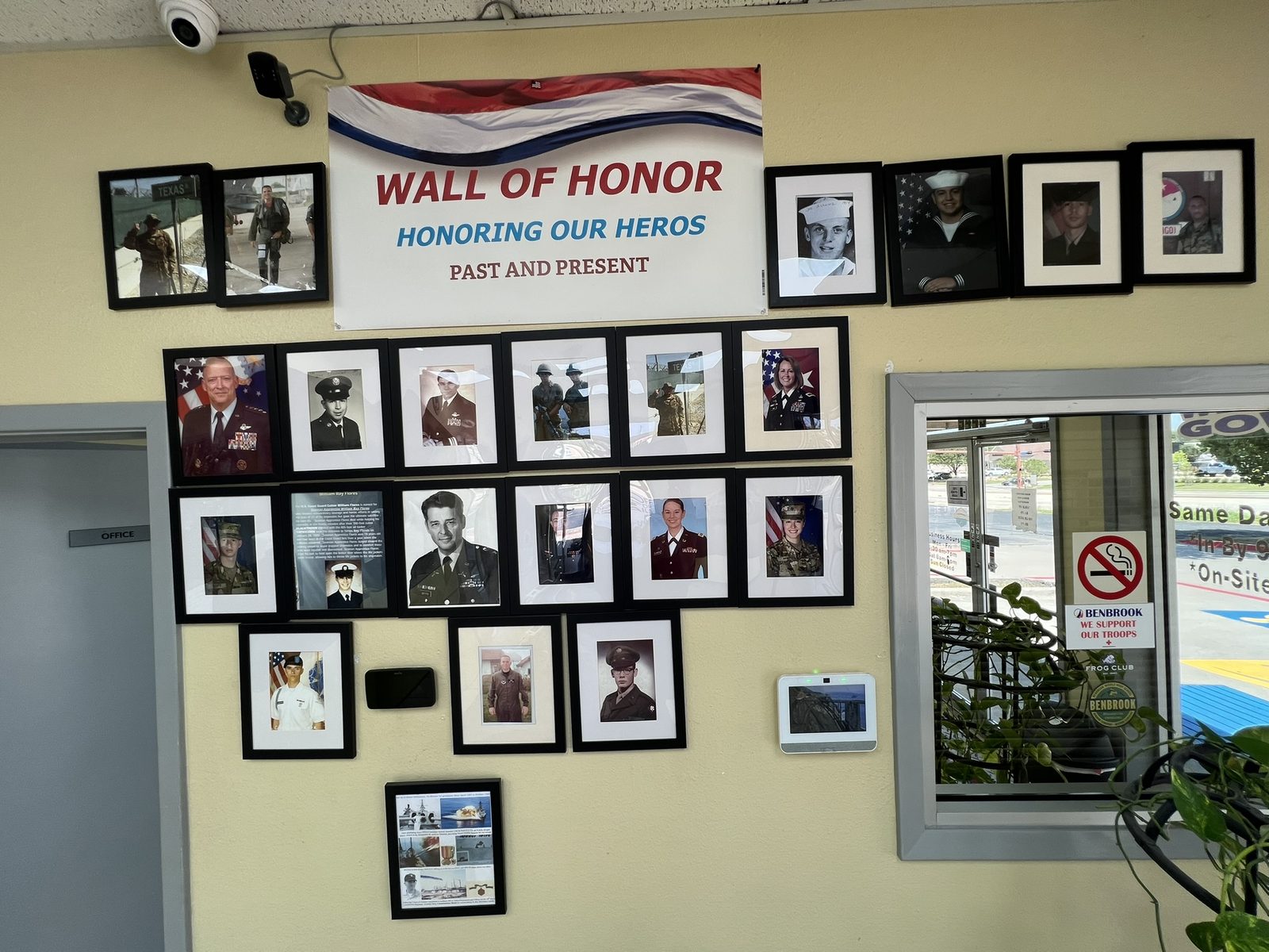 The Wall of Honor inside Dry Clean Super Center Benbrook, displaying framed photographs of service members